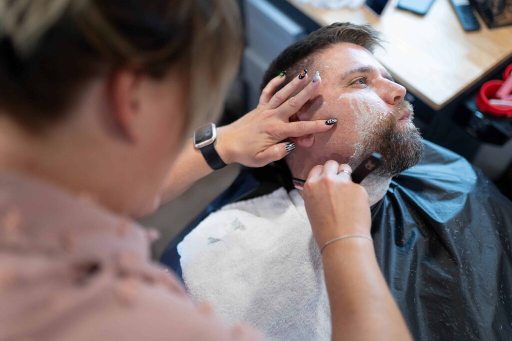 woman shaving a mans face